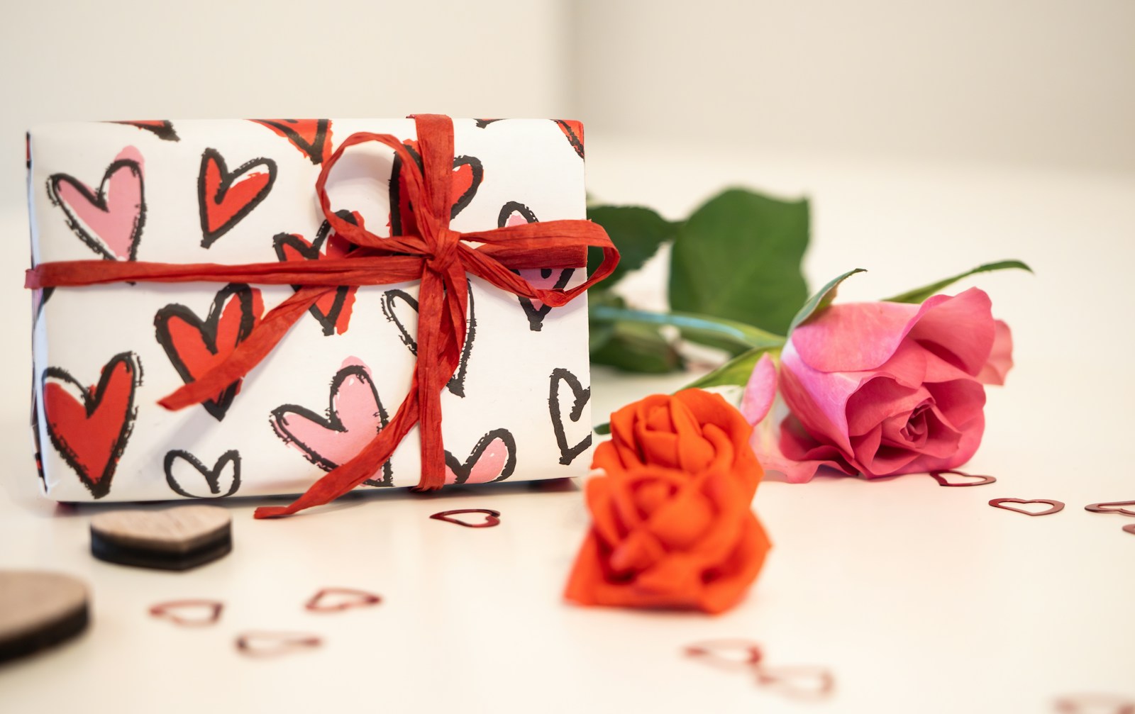 a gift wrapped in a heart pattern with a rose next to it