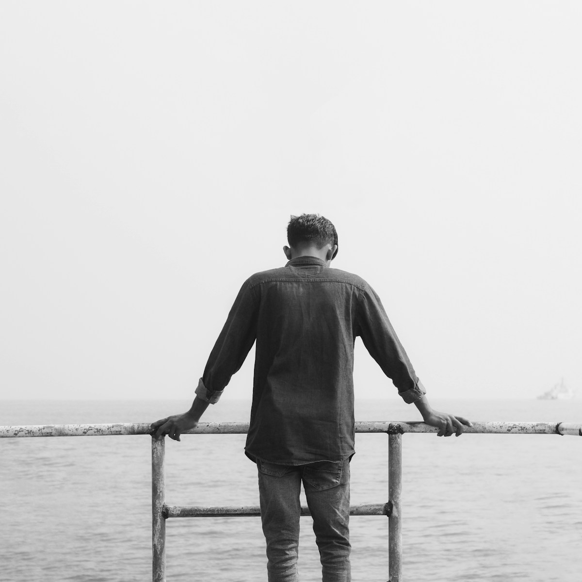 A man standing on a pier looking out at the water